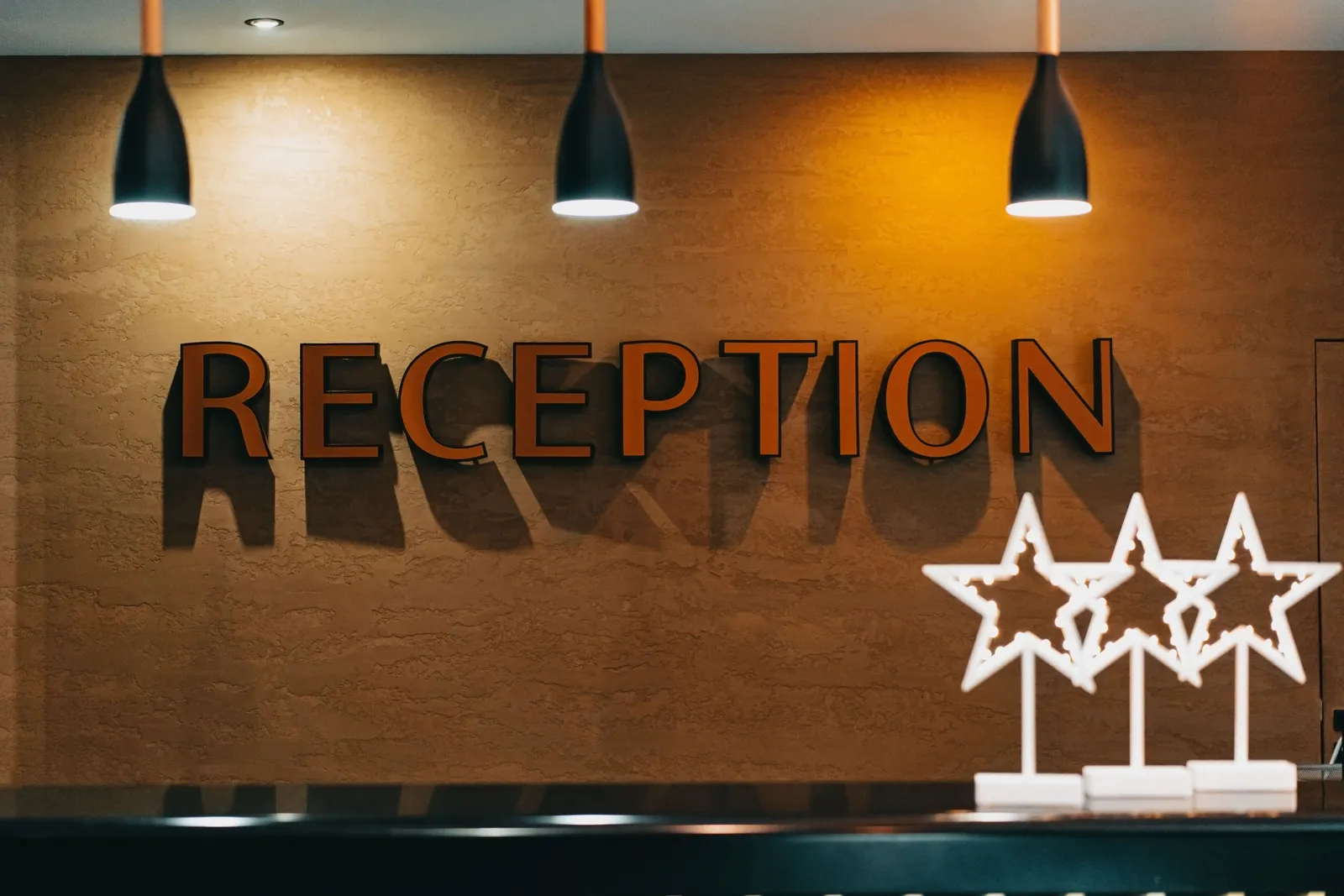 שלט עץ עם הכיתוב Reception ושלושה כוכבים בלובי מלון